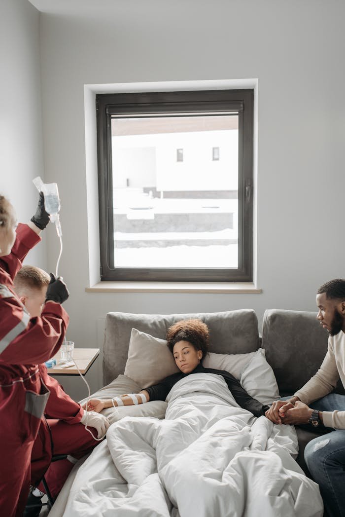 Paramedics providing medical care to a patient in a home setting with family support.